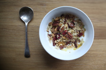 spoon near bowl of muesli with yogurt and nuts