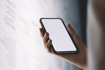 Close up view of hand holding modern smartphone with big blank screen for content template. Person using interactive internet kiosk and application on mobile phone. Copy space area for advertising