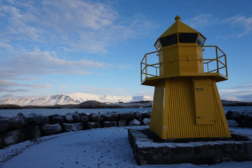 Fototapeta na wymiar yellow lighthouse in front of white mountains