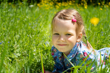 Portrait of a girl of 4 years on a green lawn. Girl on the grass in the park