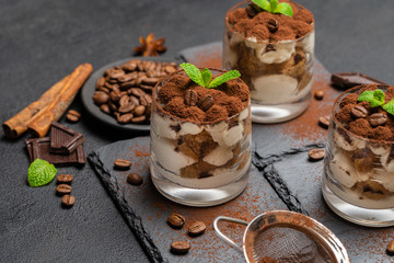 Classic tiramisu dessert in a glass on stone serving board on dark concrete background
