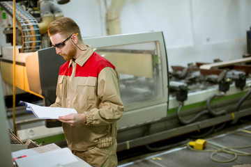 Young man with blueprints working in a factory