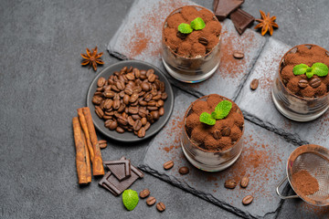 Classic tiramisu dessert in a glass on stone serving board on dark concrete background