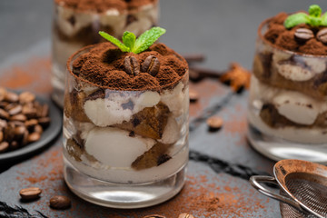 Classic tiramisu dessert in a glass on stone serving board on dark concrete background