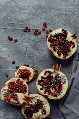 Several ripe pomegranates on a gray grunge concrete background. Grenades with large red grains lie on the concrete pavement.