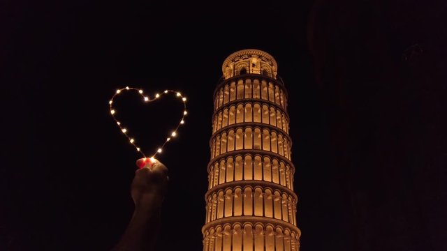 Torre di Pisa di notte con simbolo del cuore, un viaggio per coppia romantico.