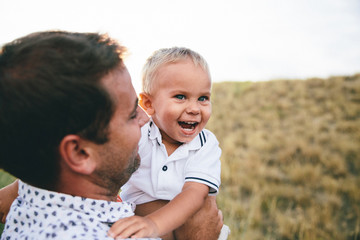 smiling toddler hugging his father and holding his neck