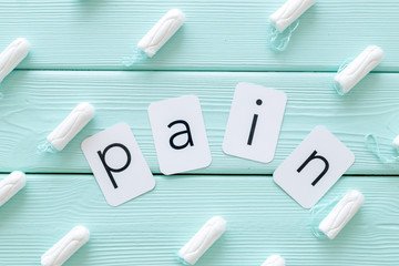 Pain copy for menstrual period concept with tampons on mint green wooden background top view pattern