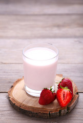 Yogurt with strawberry in glass on grey wooden background