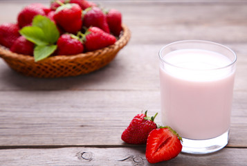Yogurt with strawberry in glass on grey wooden background
