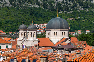 Obraz premium Red tiled roofs of old town houses in Kotor and Serbian Orthodox Church of St. Nikola , Montenegro