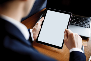 Tablet screen used by male hands sitting at a desk.