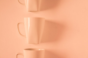 Orange coffee mugs on orange background in a vertical row with empty copyspace