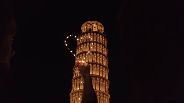 Torre di Pisa di notte con simbolo del cuore, un viaggio per coppia romantico.
