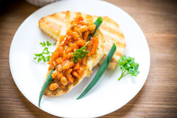 fried bread toasts with stewed beans and vegetables in a plate
