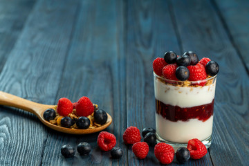 The healthy breakfast of yogurt with muesli, granola rasberry jam and fresh fruits rasberry and blueberry