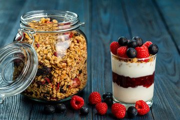 The healthy breakfast of yogurt with muesli, granola rasberry jam and fresh fruits rasberry and blueberry