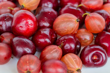 Gooseberries and wild cherry berries on a light background