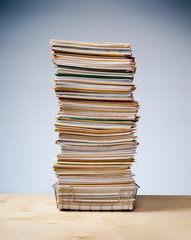 In, out tray on desk with tall stack of never ending office paperwork
