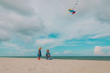 kids-boy and girl- flying a kite at sky on beach