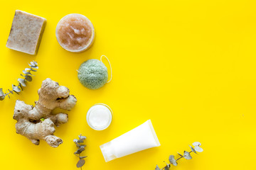 Scrabs and creams for natural cosmetic set with herbs and ginger on yellow background top view mock up