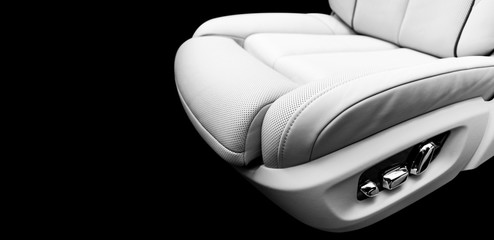 White leather interior of the luxury modern car. Perforated white leather comfortable seats with stitching isolated on black. Modern car interior details. Car detailing. Car inside. Black and white