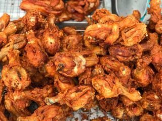 Thai street vendor sells grilled chicken legs meat at street food market chicken legs in a pan close up. 