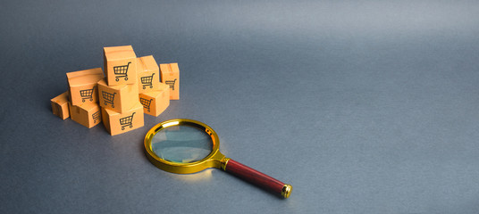 A pile of boxes and a magnifying glass. Online shopping, best offer. search for goods and services....
