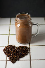 Organic natural chocolate coffee cacao smoothie beverage with chia seeds in glass jar on a black graphite slate background with coffee beans in shape of heart. Healthy diet vegetarian snack.