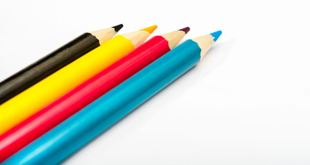 Four colored pencils. The colors cyan, magenta, yellow and black. The concept of polygraphy.