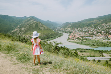 Fototapeta na wymiar Little girl looking at Mtskheta city from the hill