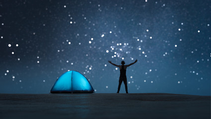 Fototapeta na wymiar The man raised his hands up. Near the glowing tent. Starry bokeh background