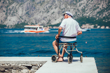 Fototapeta premium Back view of disabled senior man at beach on a sunny day