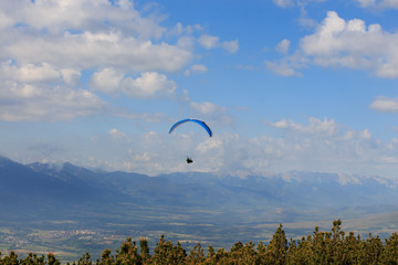 Paragliding flying through the green meadows