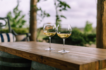 two glasses of white wine on wooden table, blurred background