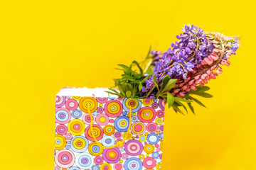 Lupine in gift colorful box. Festive surprise. Elegant gift. Gift box with lupine flowers. on yellow background