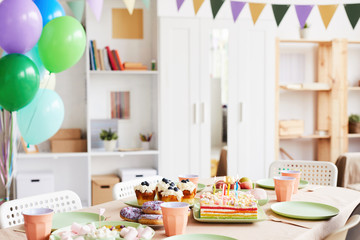 Background image of dinner table set with sweets and cake for Birthday party in decorated room,...