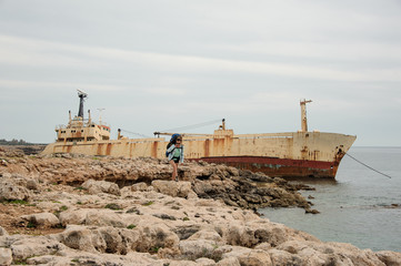 Young girl standing with a hiking backpack on the sea coast