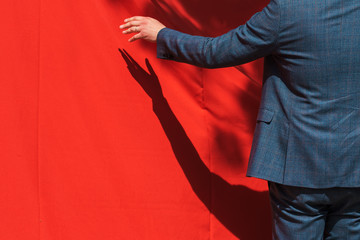 Grand opening, businessman opens red curtain to reveal product
