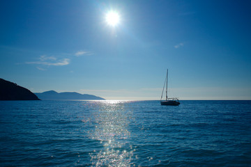 Evening sailboat mooring at sea with sun