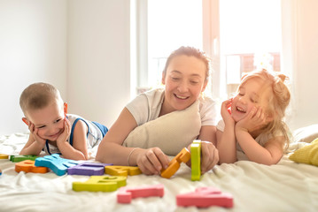Mother having fun with kids while learning them letters at home
