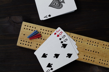playing cards and cribbage board on black background