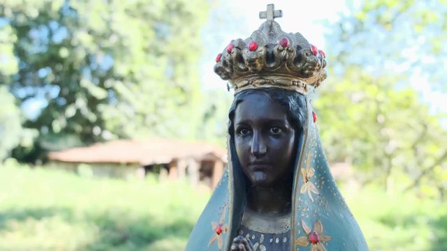 Sculpture of the image of "Nossa Senhora Aparecida" the patroness of Brazil. Image with gimbal on nature background on sunny day.