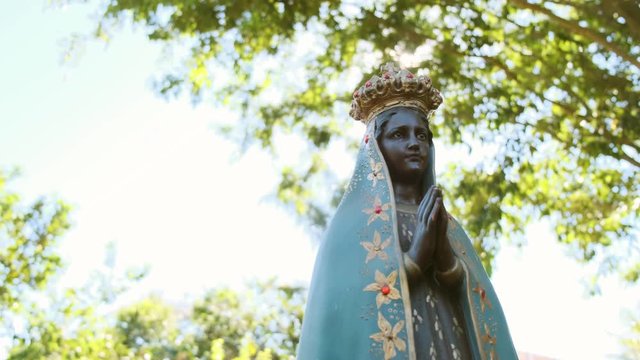 Sculpture of the image of "Nossa Senhora Aparecida" the patroness of Brazil. Image with gimbal on nature background on sunny day.