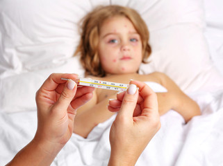 Chickenpox in a 3 year old boy lying in bed, high temperature, thermometer