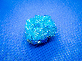 Geological specimen of natural blue layered mineral Covellite (aka covelline) - semiprecious stone and copper ore, on blue background