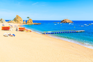 Azure blue water on idyllic beach with fishing boats in Tossa de Mar town, Costa Brava, Spain