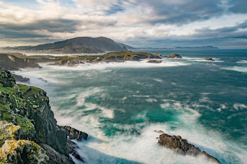 paisaje de rocas y mar con cielo cubierto y mar fuerte con espuma visible
