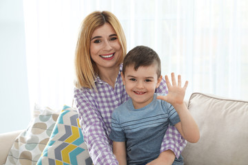 Mother and her son using video chat against light background, view from web camera