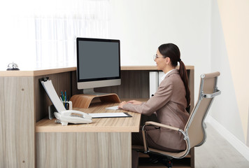 Portrait of receptionist working at desk in modern hotel